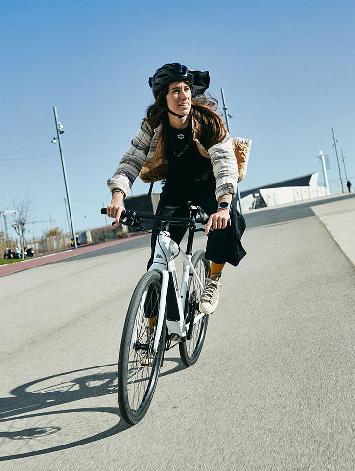 JobRadlerin fährt sportlich auf Strasse und legt sich in die Kurve mit blauem Himmel